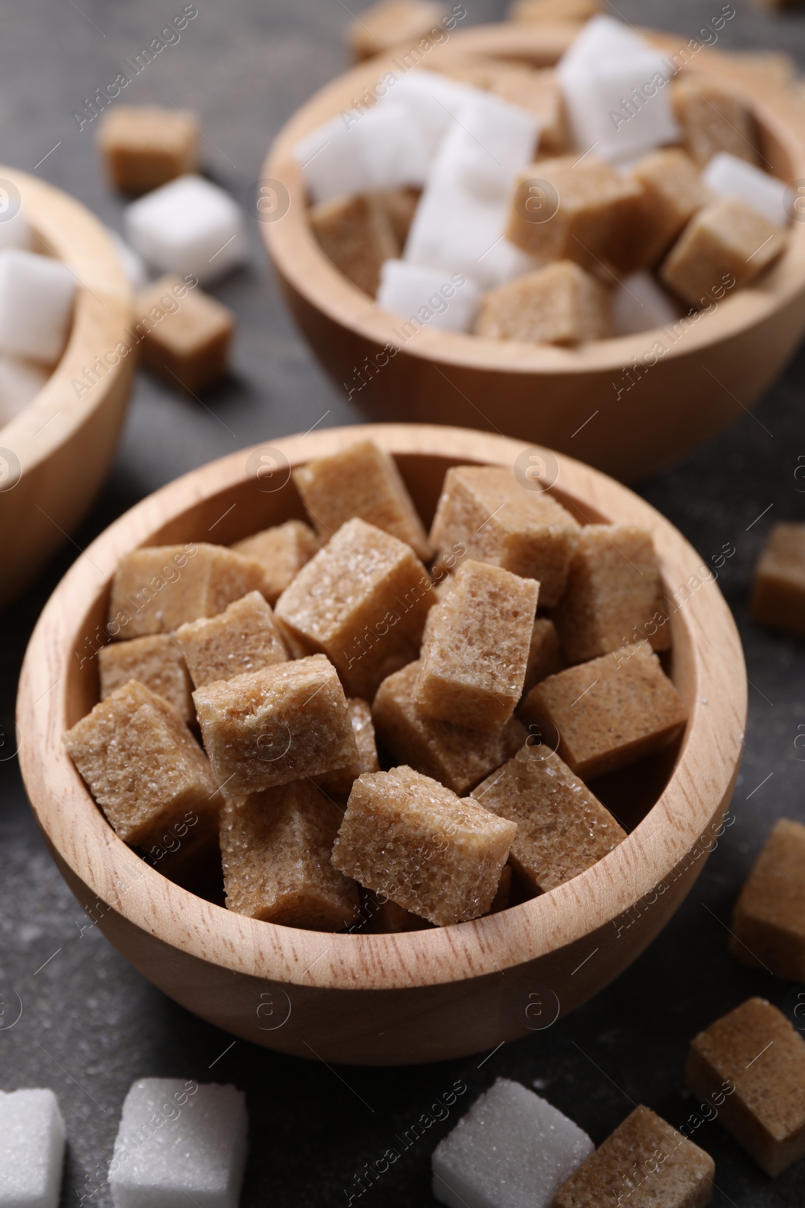 Photo of Different types of sugar in bowls on table, closeup