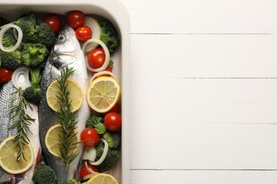 Photo of Raw fish with vegetables and lemon in baking dish on white wooden table, top view. Space for text