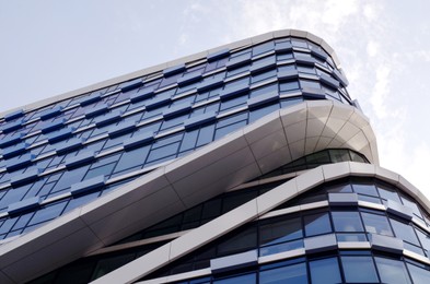 Exterior of beautiful modern skyscraper against blue sky, low angle view