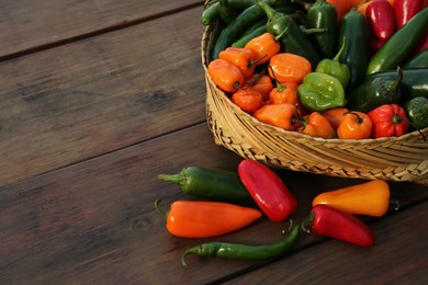 Photo of Many different fresh chilli peppers on wooden table, space for text