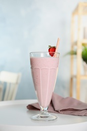 Photo of Tasty fresh milk shake with strawberry on white table indoors