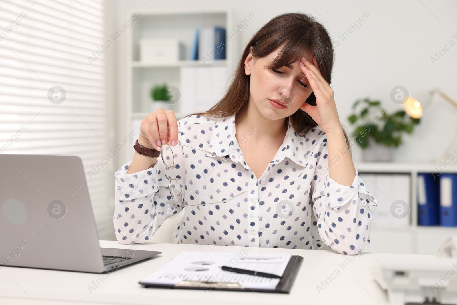 Photo of Overwhelmed woman sitting at table with laptop in office