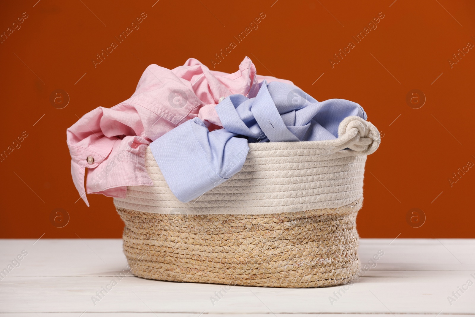 Photo of Laundry basket with clothes near brown wall