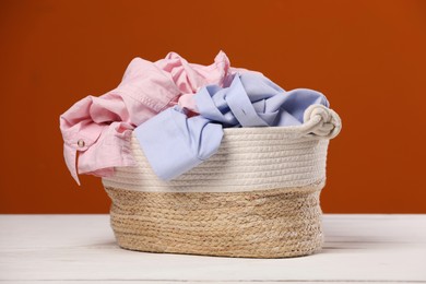 Photo of Laundry basket with clothes near brown wall