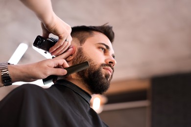 Photo of Professional hairdresser working with client in barbershop, low angle view