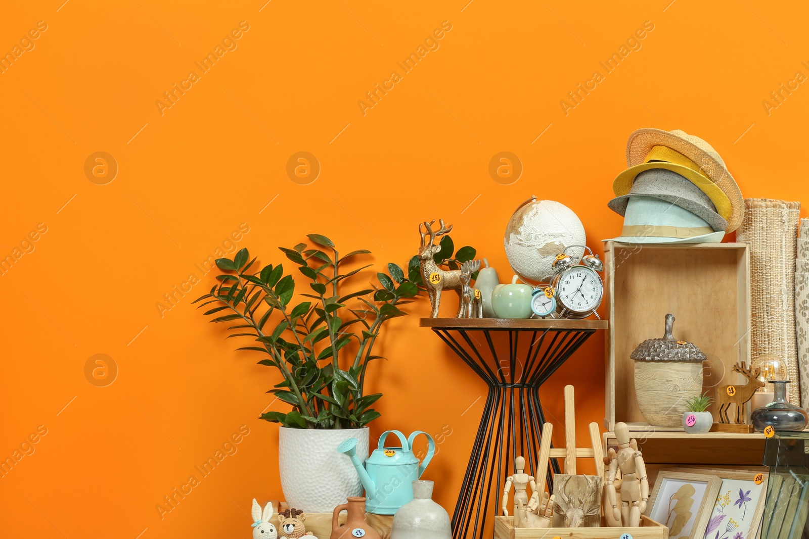 Photo of Many different items near orange wall. Garage sale