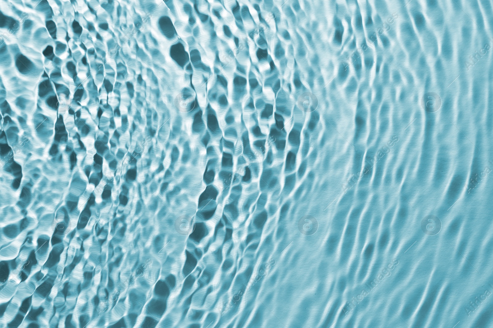 Image of Rippled surface of clear water on light blue background, closeup