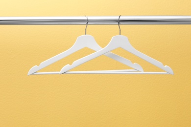 Photo of Clothes hangers on metal rail against color background