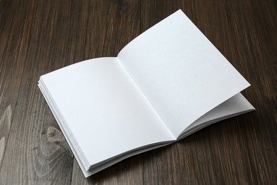 Photo of Open blank paper brochure on wooden table. Mockup for design