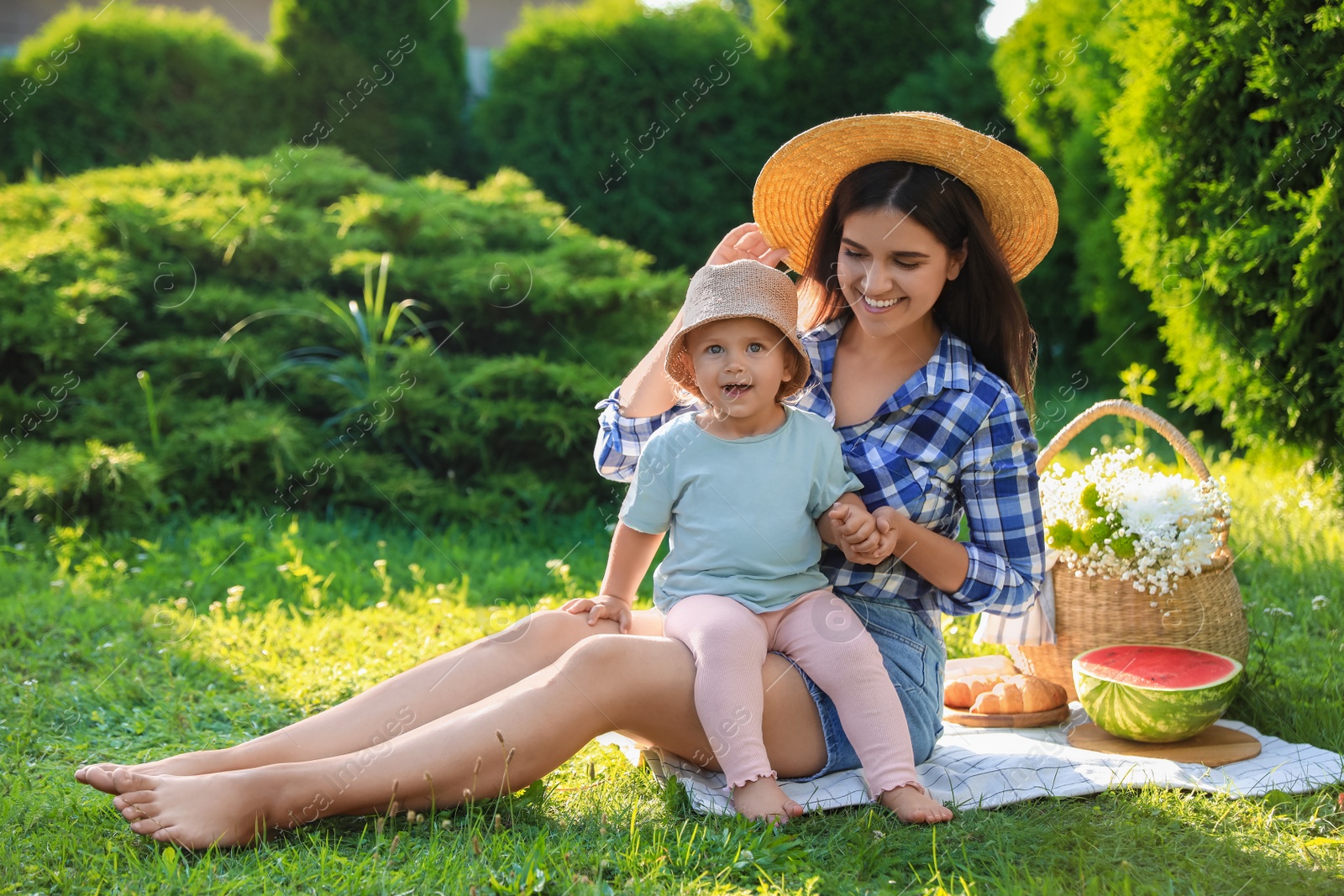 Photo of Mother with her baby daughter having picnic in garden on sunny day