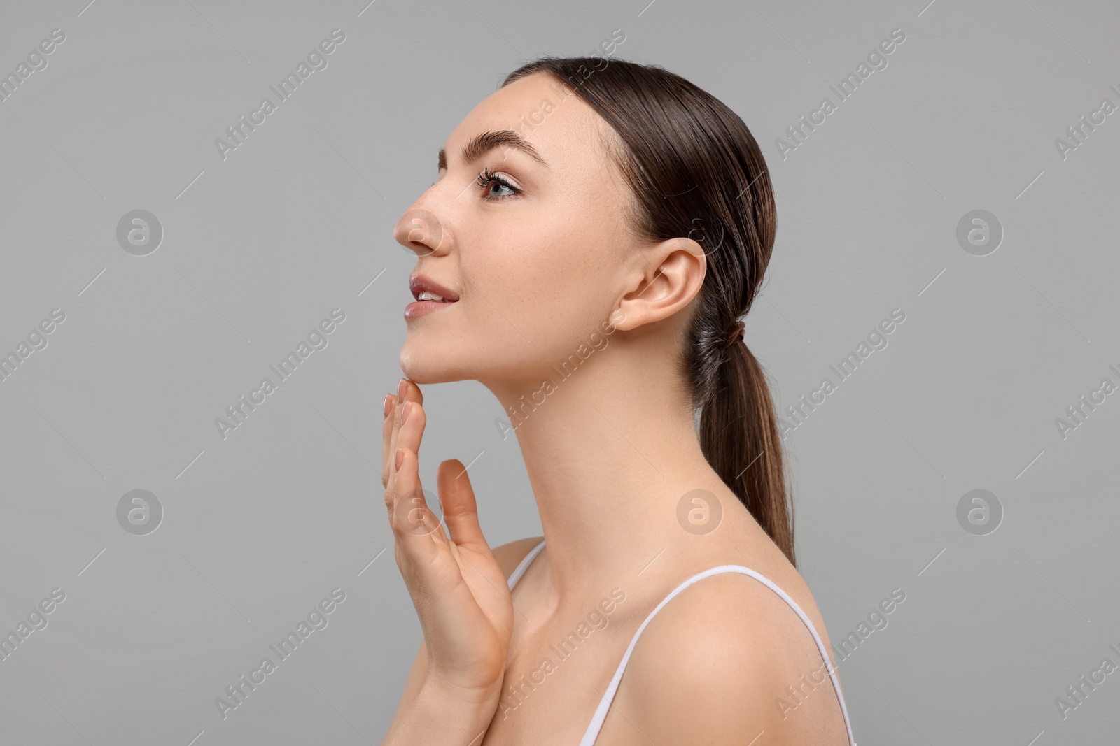 Photo of Beautiful woman touching her chin on grey background