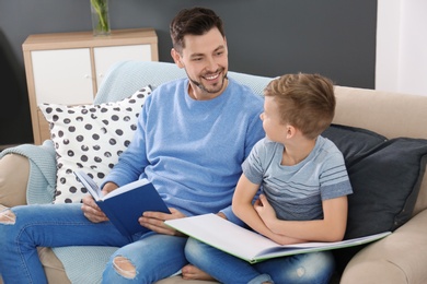 Photo of Little boy and his dad reading books at home