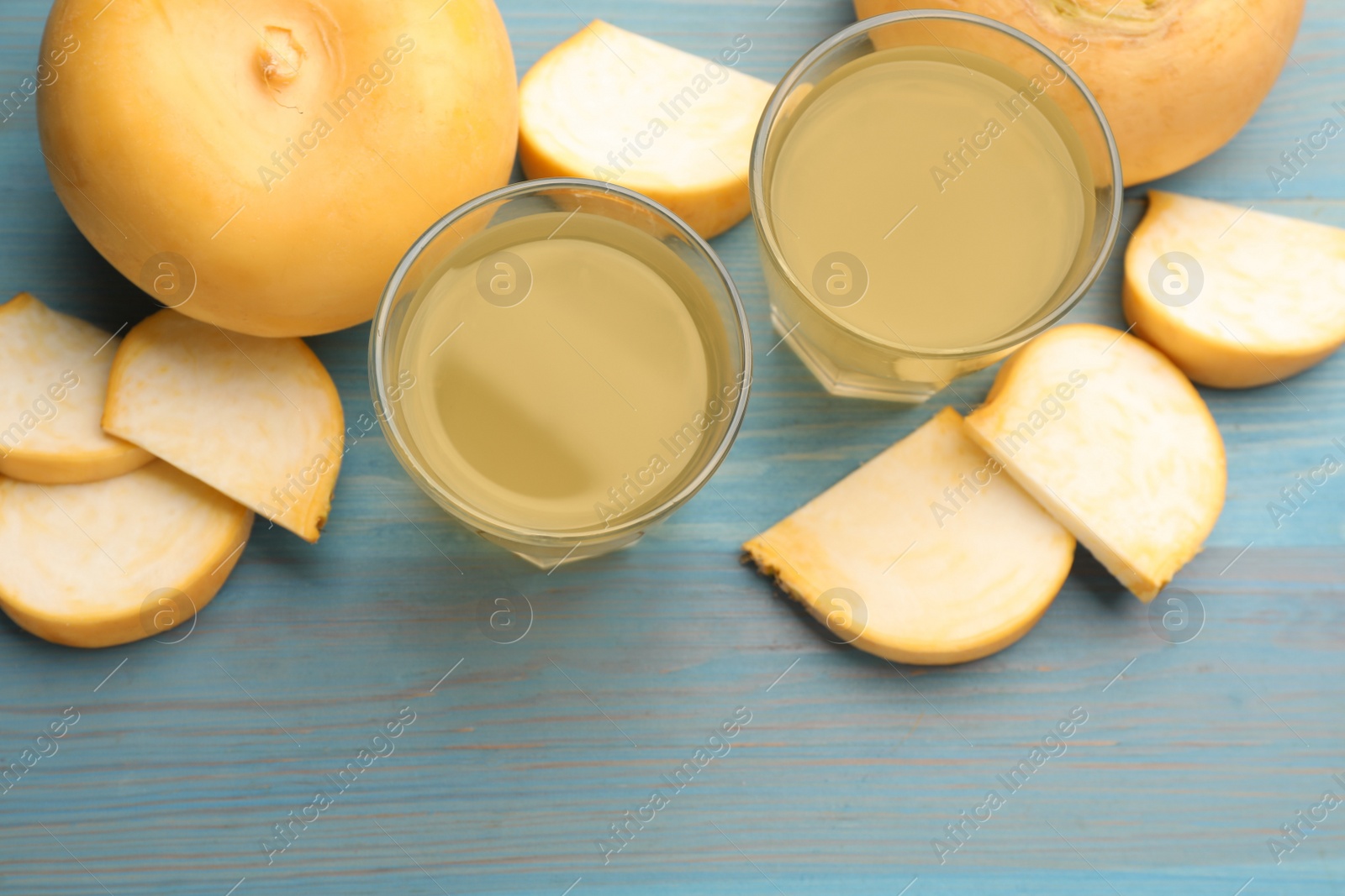 Photo of Glasses of freshly made turnip juice on turquoise wooden table, flat lay