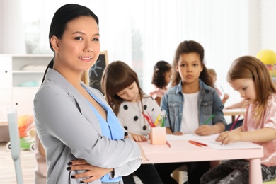 Image of Happy Asian woman in classroom with children