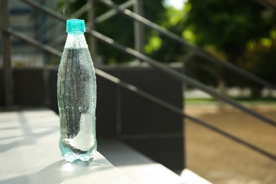 Plastic bottle of cold pure water outdoors. Space for text