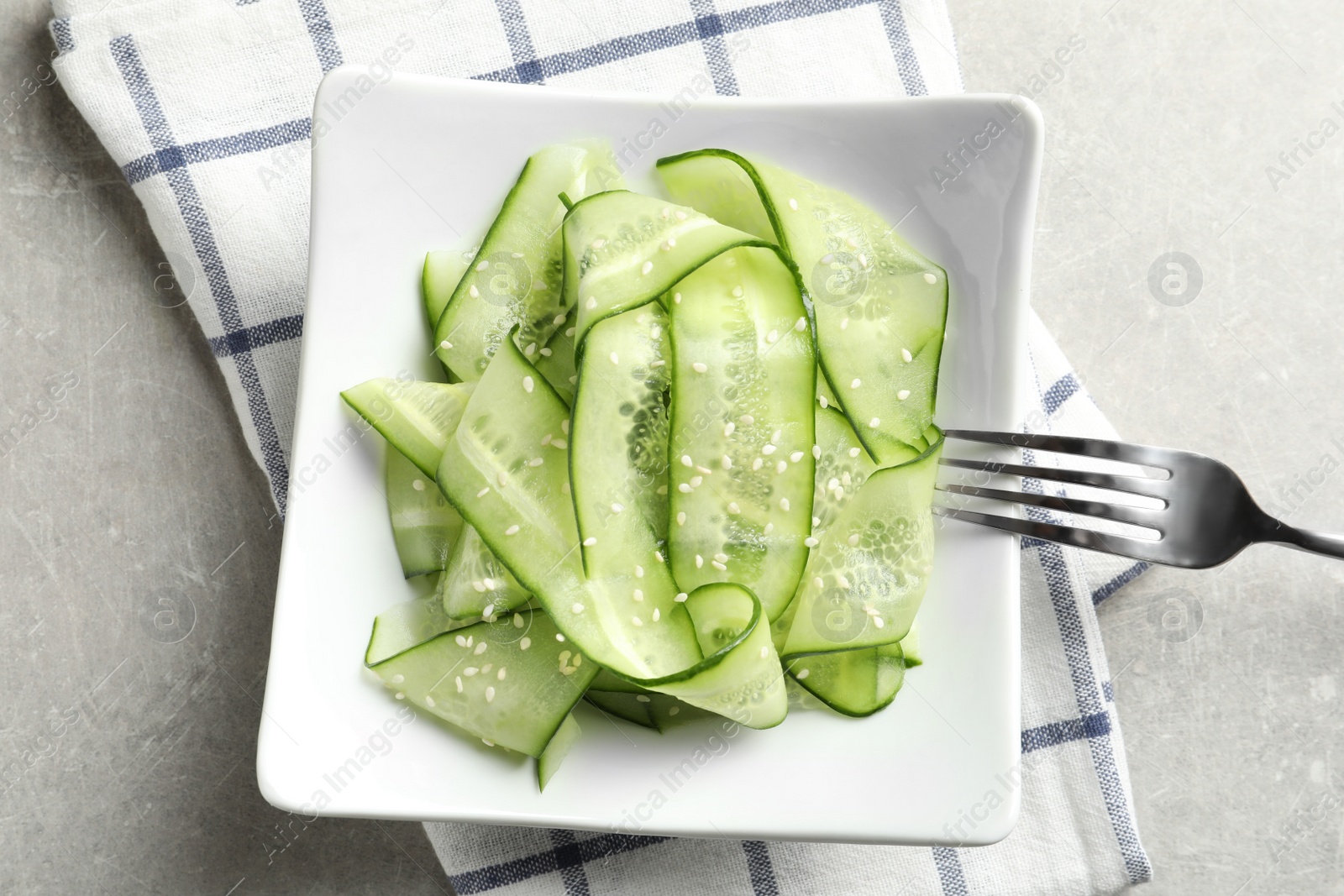 Photo of Plate with delicious cucumber salad served on grey table, top view