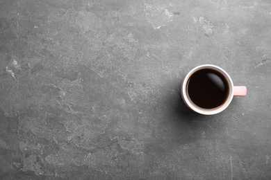 Photo of Ceramic cup with hot aromatic coffee on grunge background, top view