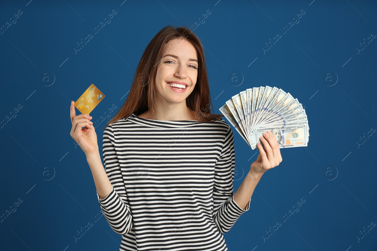 Photo of Happy young woman with cash money and credit card on blue background