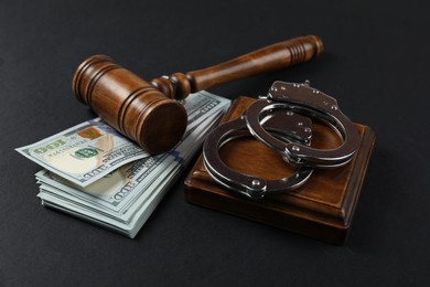 Photo of Judge's gavel, money and handcuffs on black background