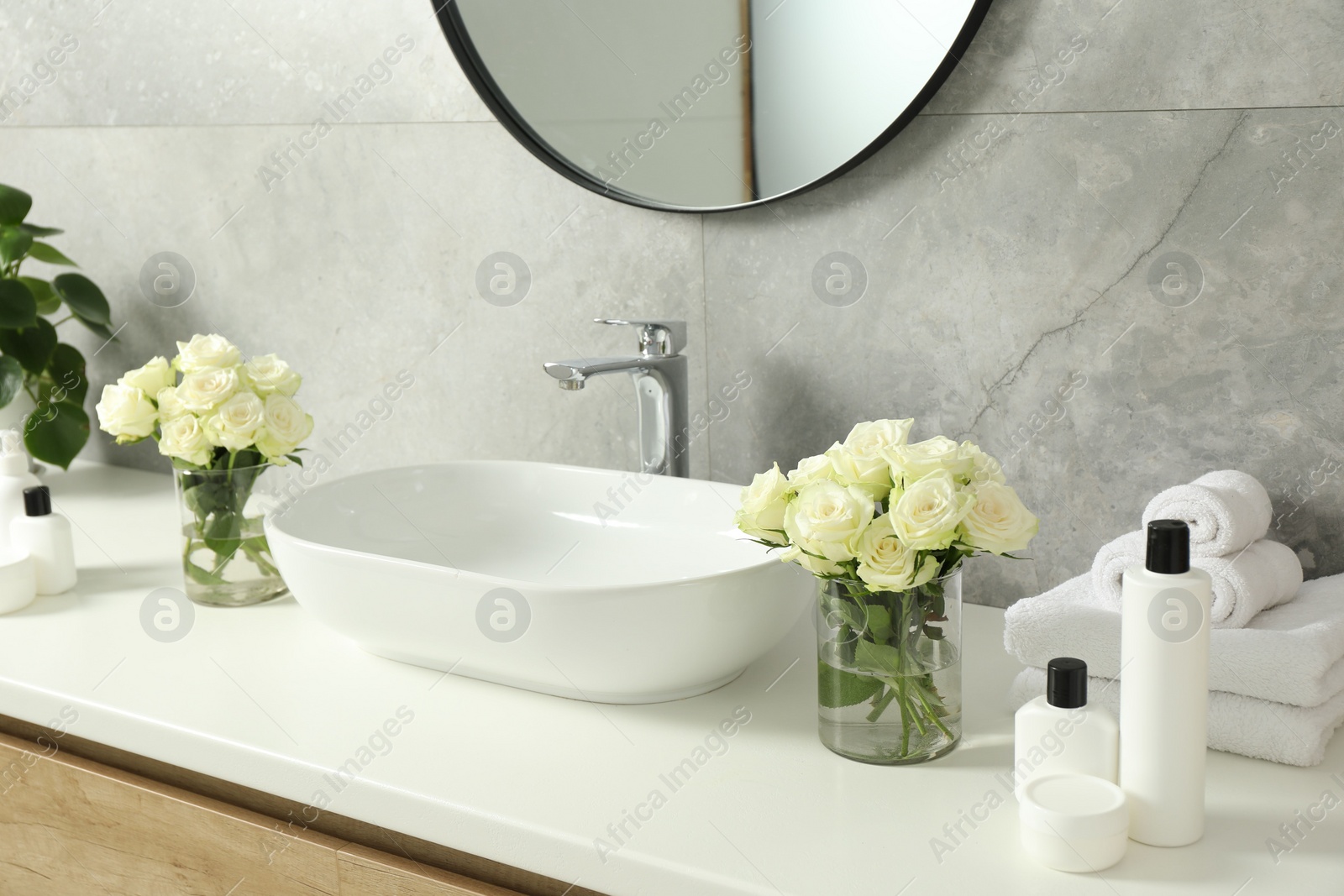 Photo of Beautiful roses and bath accessories near sink in bathroom