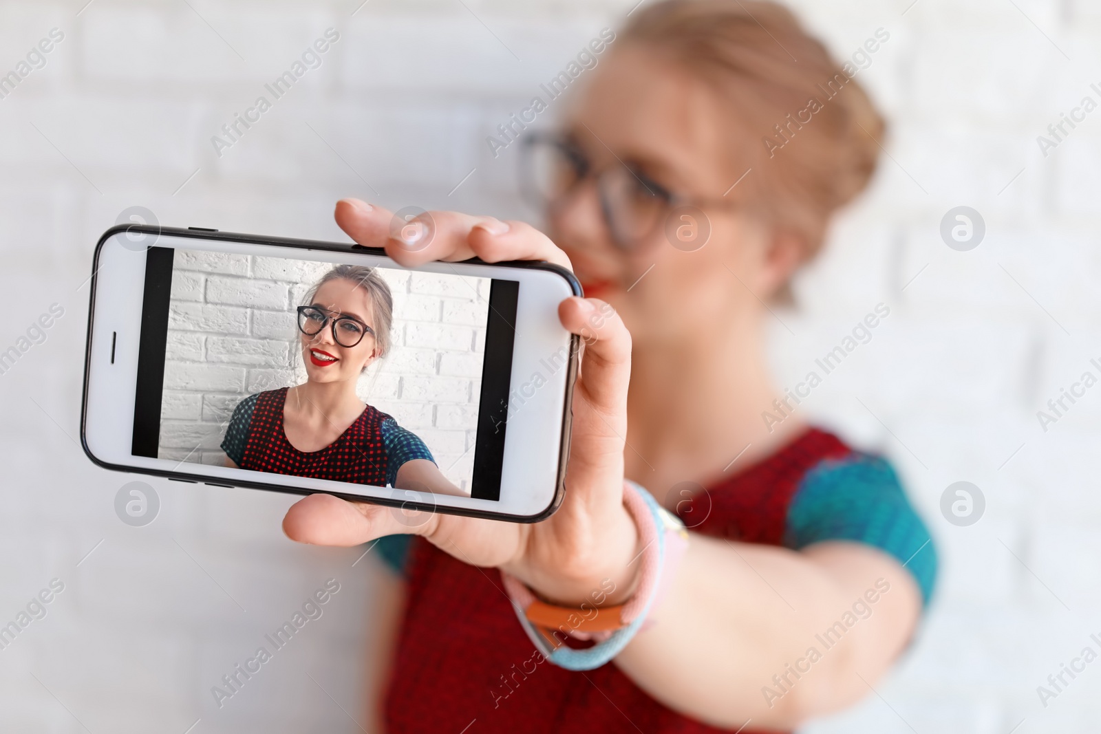 Photo of Attractive young woman taking selfie near brick wall, closeup