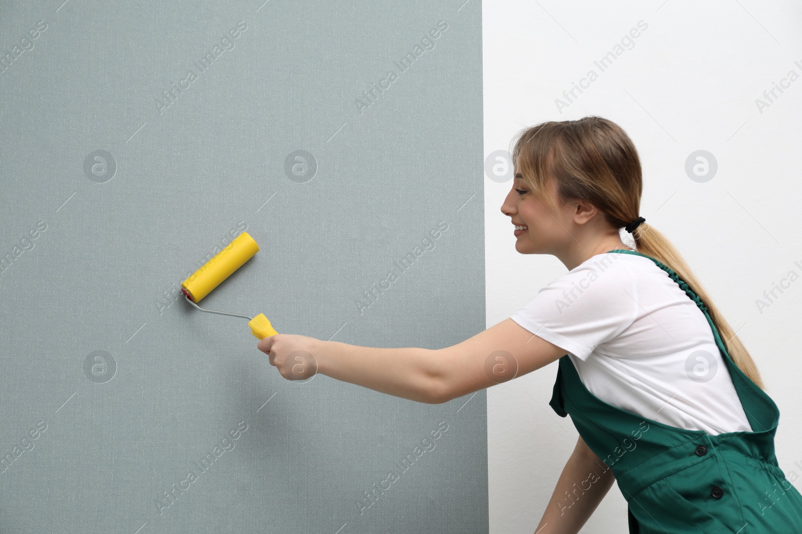 Photo of Worker hanging stylish wall paper sheet indoors