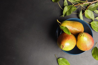 Photo of Bowl with ripe juicy pears on dark stone table, flat lay. Space for text