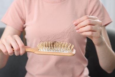 Woman untangling her lost hair from brush, closeup. Alopecia problem