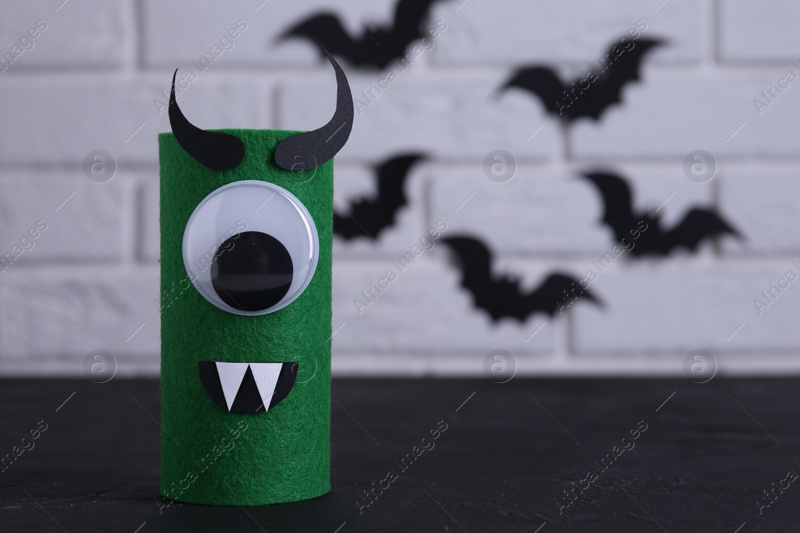 Photo of Spooky monster on black table, space for text. Handmade Halloween decoration