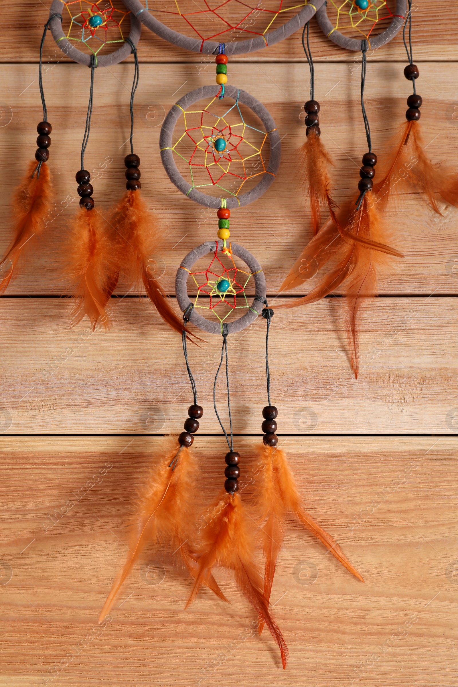 Photo of Beautiful dream catcher hanging on wooden wall, closeup