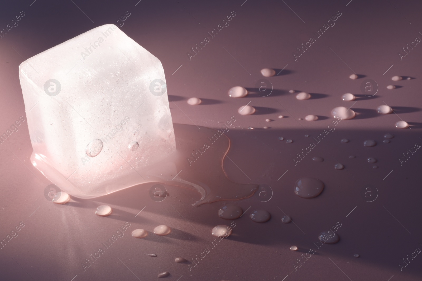 Photo of Crystal clear ice cube on pink background, space for text