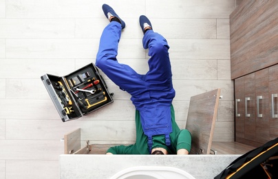 Male plumber repairing kitchen sink, top view