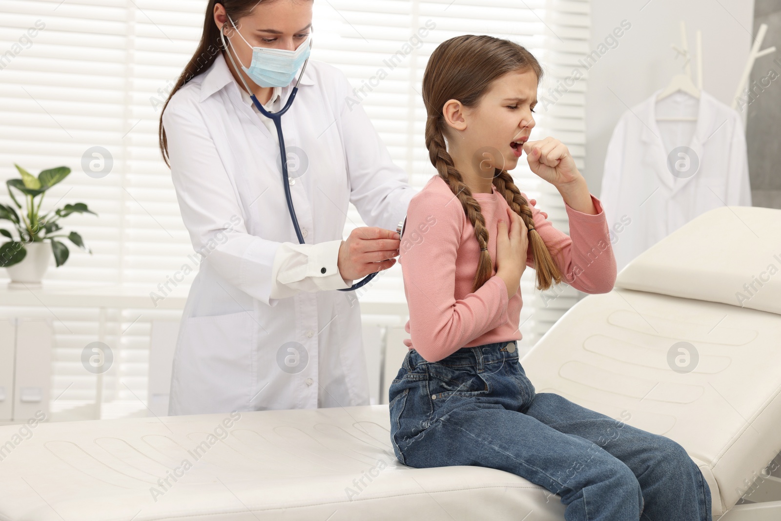 Photo of Doctor examining coughing girl in hospital. Cold symptoms