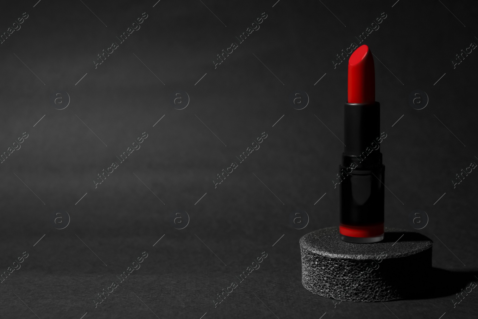 Photo of Beautiful glossy red lipstick on black background, space for text