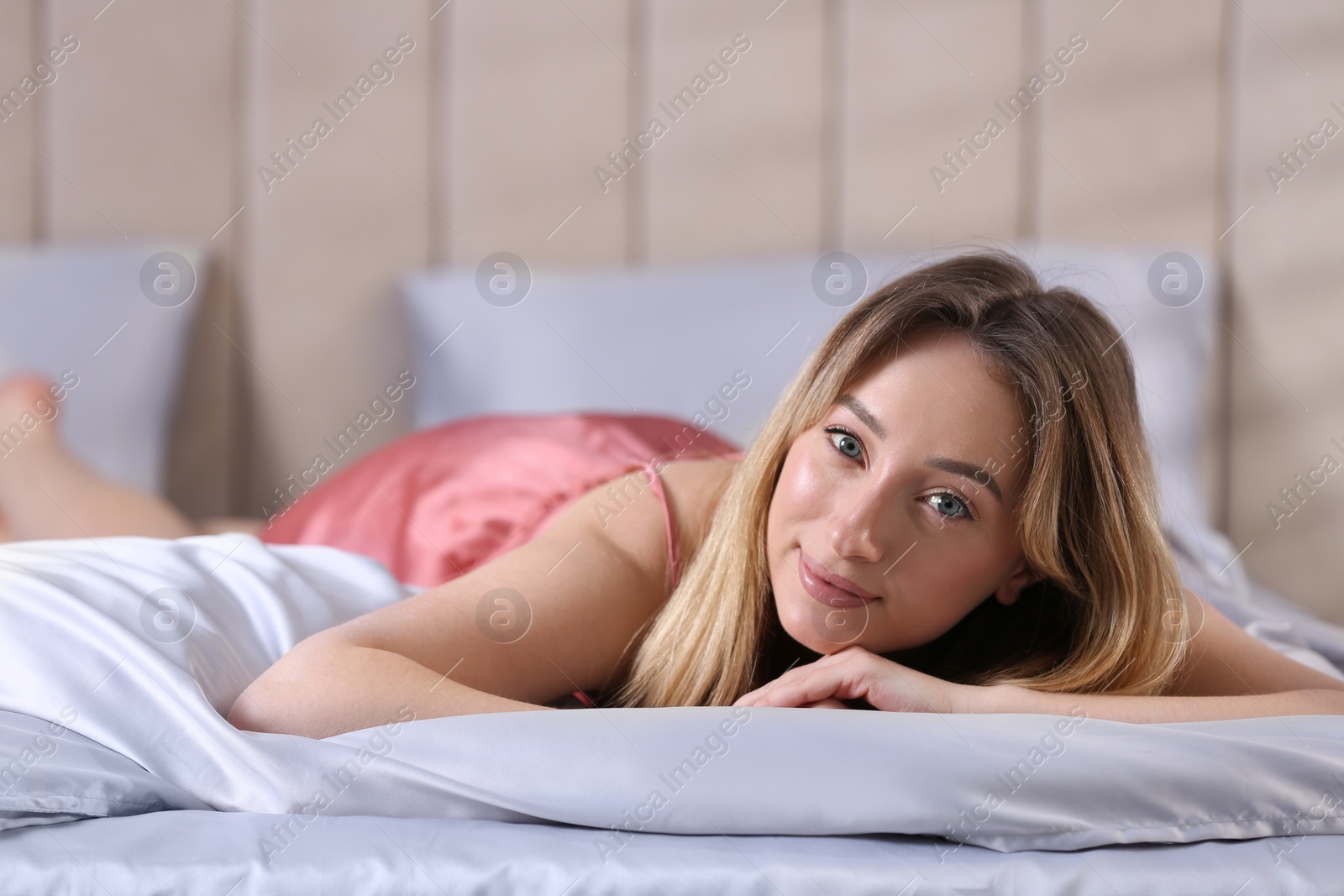 Photo of Young woman lying on comfortable bed with silky linens, space for text