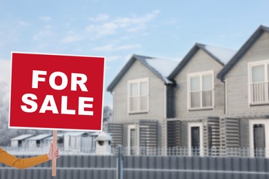 Image of House for sale. Woman holding signboard near beautiful house outdoors, closeup