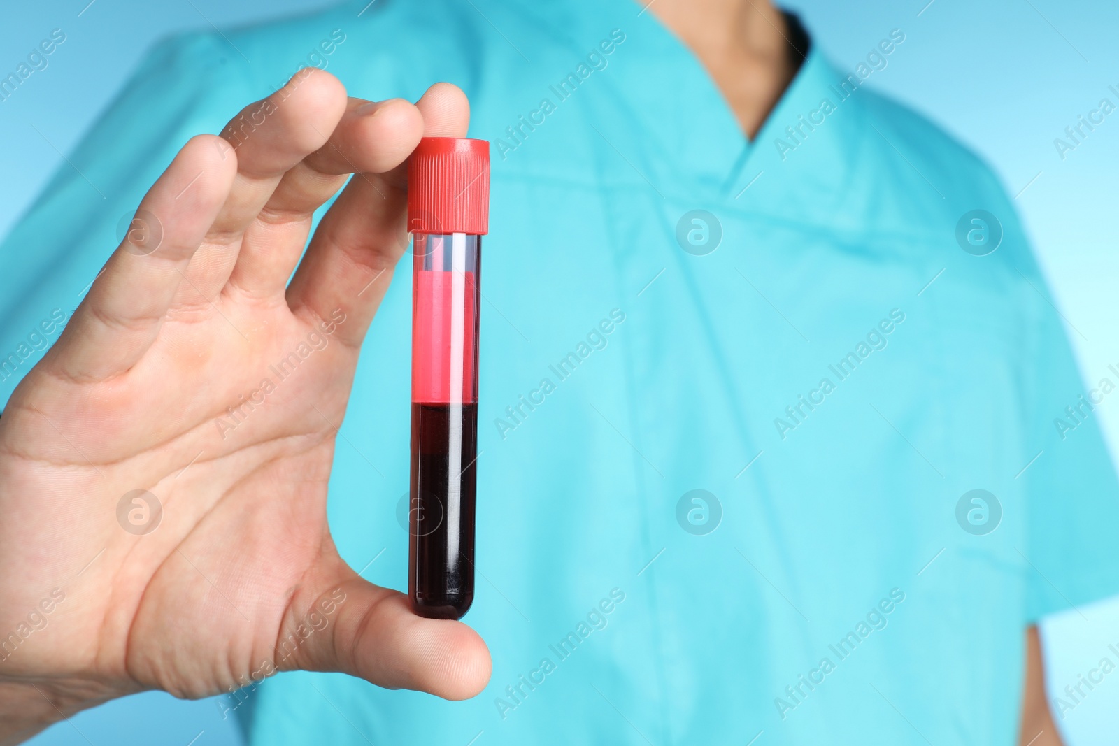 Photo of Male doctor holding test tube with blood sample on color background, closeup. Medical object