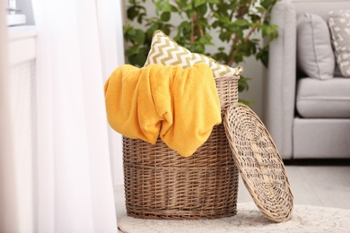 Photo of Basket with plaid and pillow near sofa indoors