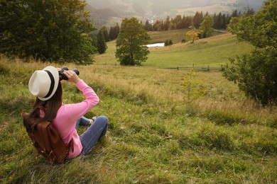 Photo of Young woman with binoculars in nature, space for text