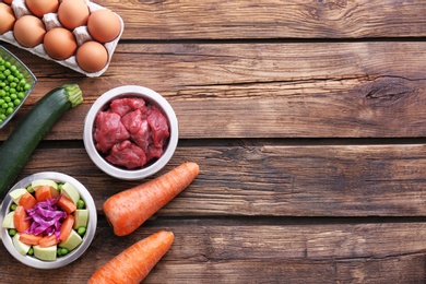 Flat lay composition with healthy dog food on wooden background. Space for text