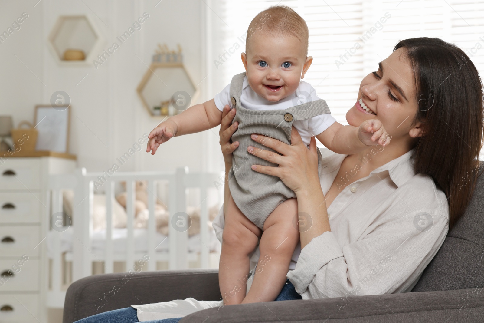 Photo of Happy young mother with her baby in armchair at home