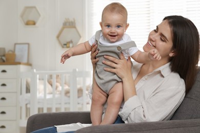 Photo of Happy young mother with her baby in armchair at home