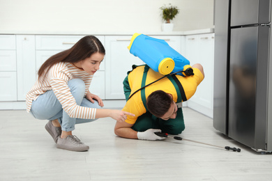 Woman showing insect traces to pest control worker in kitchen