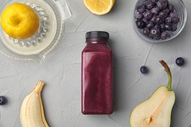 Photo of Flat lay composition with ingredients for delicious acai cocktail and bottle of juice on gray table