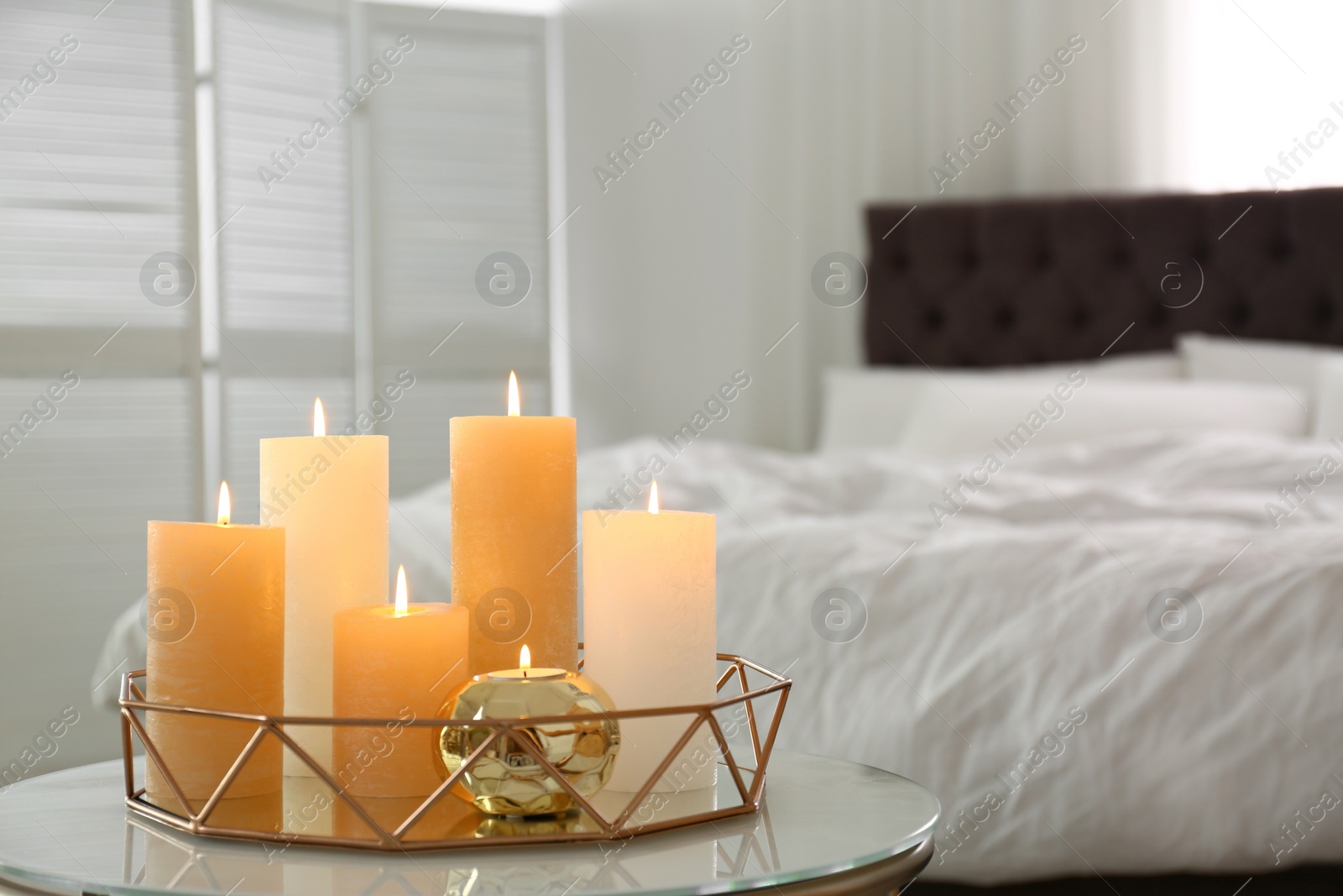 Photo of Golden tray with burning candles on table in bedroom