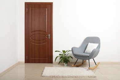 Photo of Modern room interior with brown door and rocking chair. Space for text