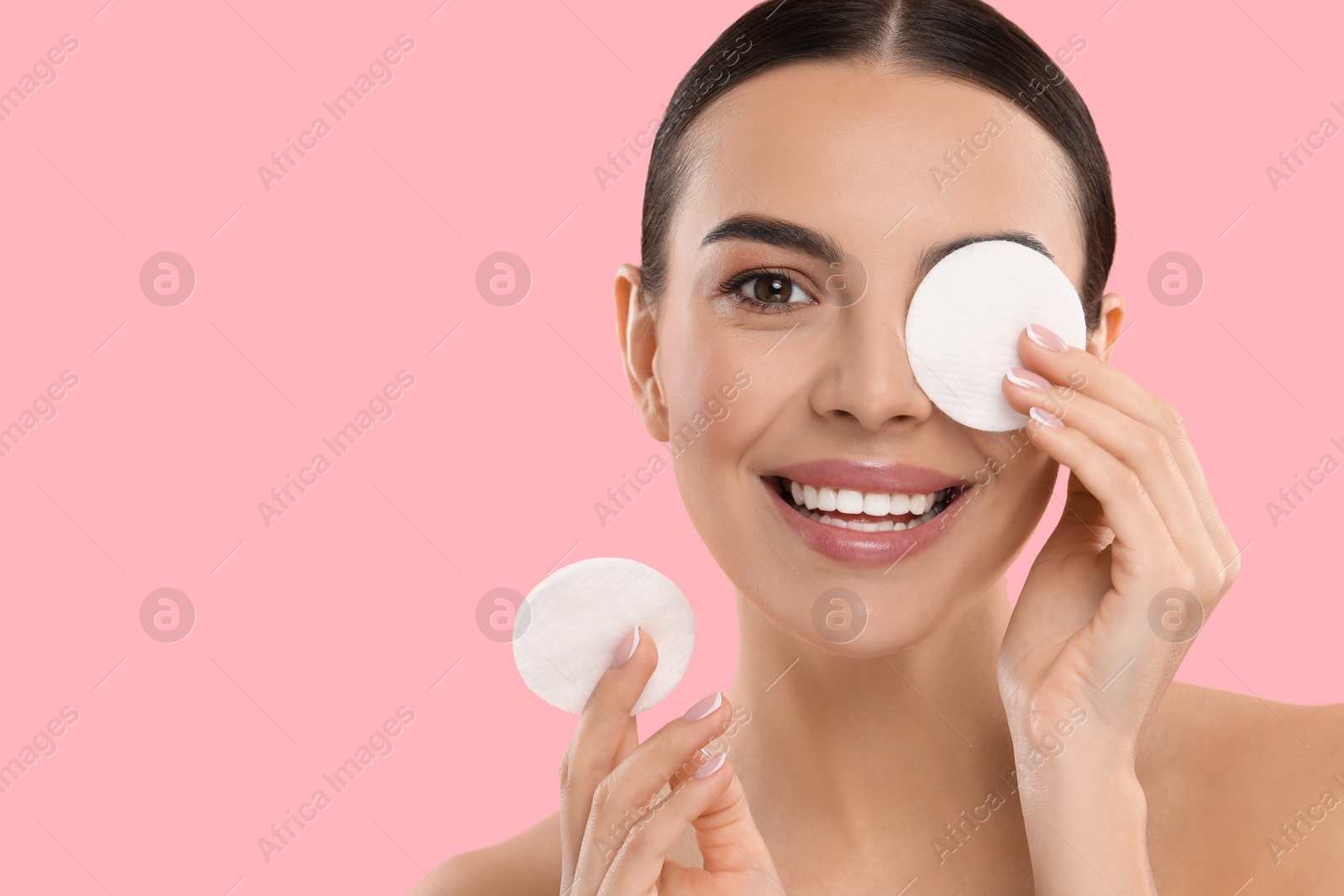 Photo of Beautiful woman removing makeup with cotton pads on pink background. Space for text