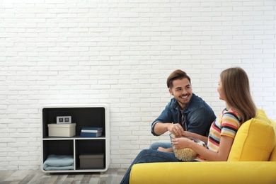 Photo of Couple with snack watching TV together on sofa in living room