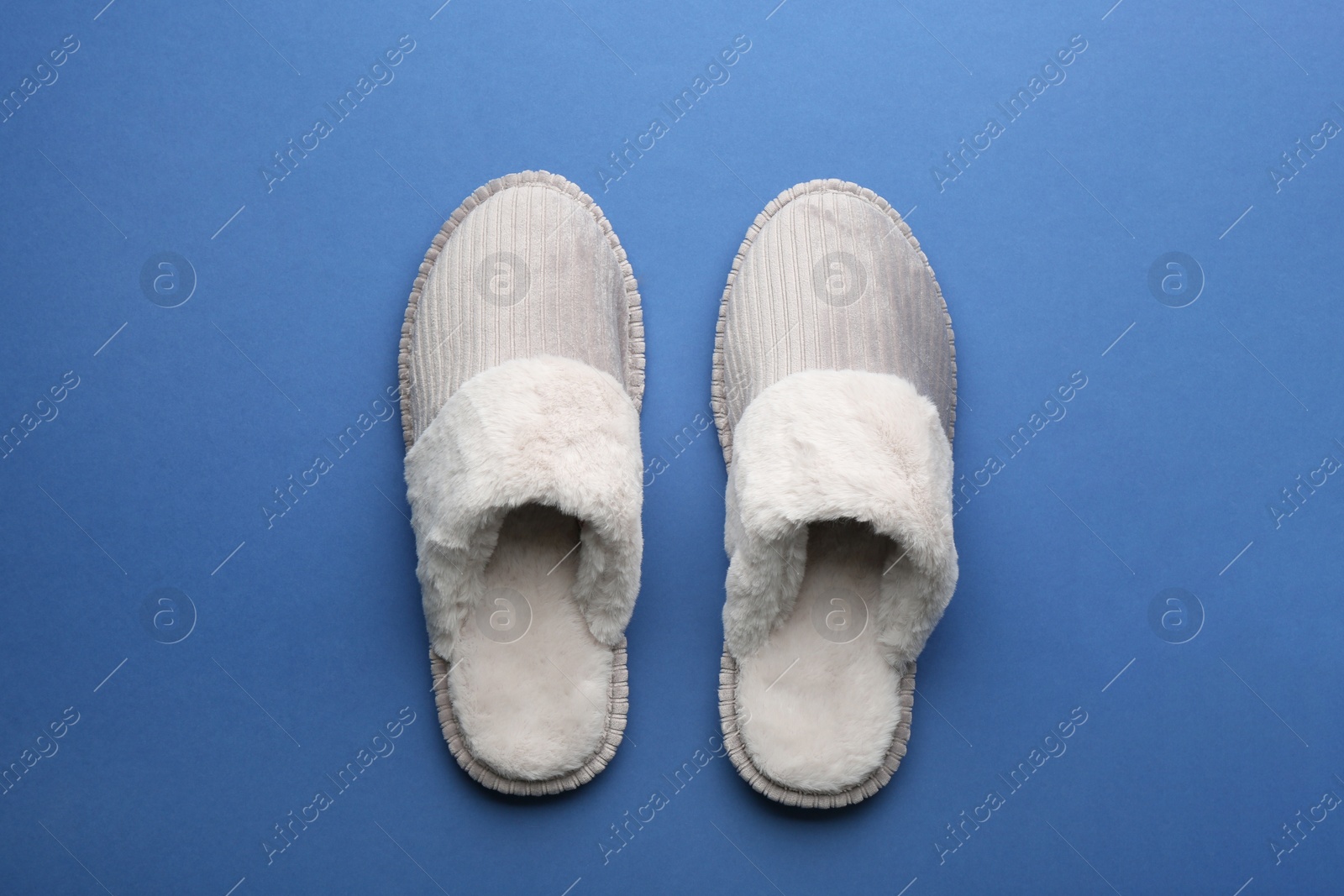 Photo of Pair of soft slippers on blue background, flat lay
