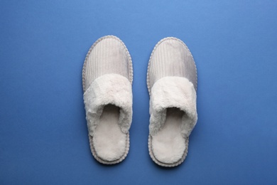 Pair of soft slippers on blue background, flat lay
